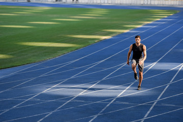 Fototapeta premium fast handsome runner exercising on running track at stadium
