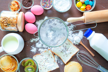 Baking cake in rural kitchen - dough recipe ingredients (eggs, flour, milk, butter, sugar) on vintage wooden table from above. Background layout with free text space