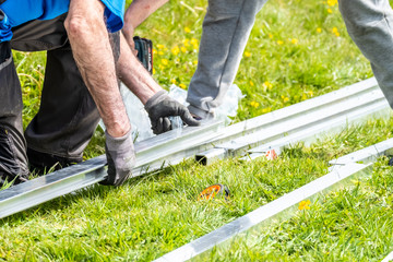 Two engineers putting together aluminium rails for photovoltaic system