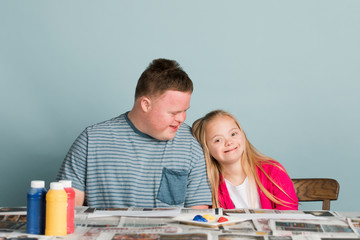 Cute siblings with down syndrome playing with paint