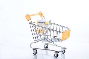 Yellow shopping cart with Covid-19 vaccine on a white background, isolated, close up.
Be careful with coronavirus while shopping!
