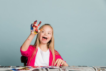 Cute girl with Down Syndrome playing with paints