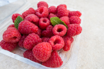 close up of raspberries in a plastic container