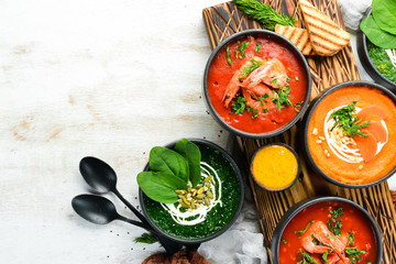 Set of colored tasty soups on white wooden background. Spinach, tomato and carrot soup. Healthy food.