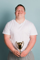 Cute boy with down syndrome holding a trophy