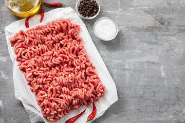 fresh raw ground meat in white paper on ceramic background