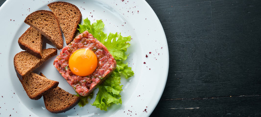 Veal tartar with egg yolk and black bread. Top view. Free space for your text.