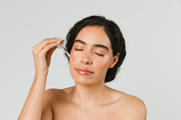 Young woman applying serum on her face