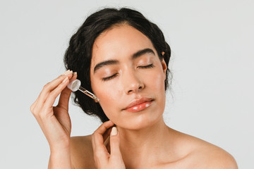 Young woman applying serum on her face