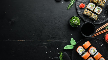 Set of sushi rolls with ginger, wasabi and soy sauce on a black stone background. Japanese...