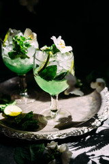 Cold cocktail with mint, lime and ice in a glass