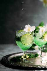 Cold cocktail with mint, lime and ice in a glass