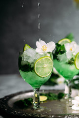 Cold cocktail with mint, lime and ice in a glass