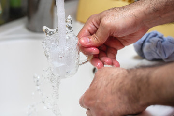 man washing glass cup on kitchen