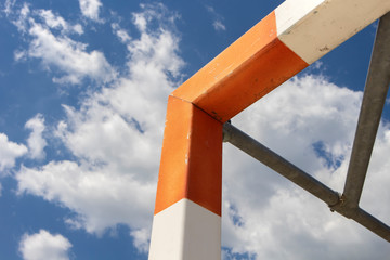 Orange and white goal bars on the outdoor, sport playground under the beautiful, summer blue sky