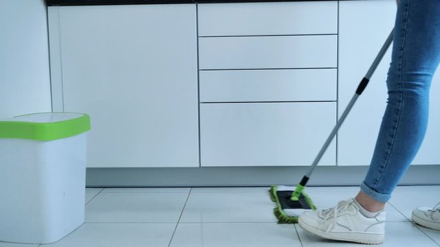 Woman washing white kitchen floor with special swob, cleaning service, close-up