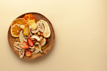  Dried fruit chips on a wooden plate. The concept of a healthy snack without sugar, dessert for vegetarians. Copy space.