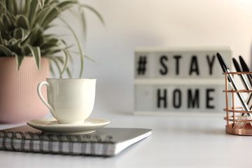 Home office desc concept during self quarantine as preventive measure against virus. Stay safe concept. Cup of coffee, clock, stationary, home plant on white background