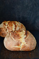 Homemade Freshly Baked Country Bread  made from wheat and whole grain flour on a dark background. French Freshly baked bread. Slicing homemade bread 