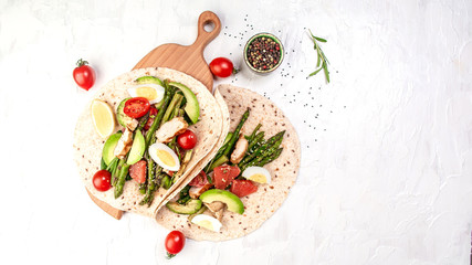 Stack whole grain tortillas. Ingredients for Flatbread Paratha roti cherry tomatoes, asparagus, on light gray background. Top view. Long banner format. space for text