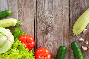 Assorted green vegetables and red tomatoes on a wooden background. Top view with copy space capability.