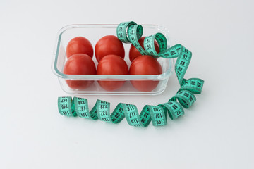 blue measuring tape lie near transparent box with six tomatoes.  dieting concept. way of loosing weight and calories control, healthy eating and lifestyle.