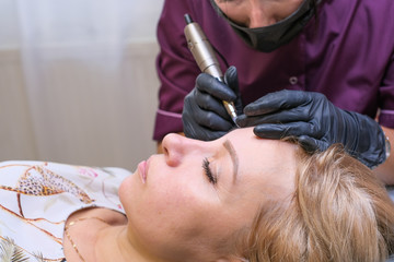 master brow artist makes permanent eyebrow makeup in the technique of powder browsers....