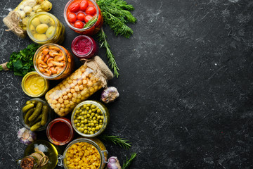 Food stocks in glass jars. Pickled vegetables. On a black background. Top view.