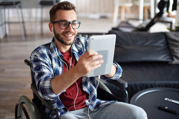 Handicapped man using tablet and earphones