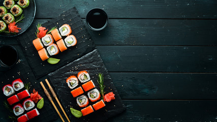 Set of colored sushi in black plates. Japanese food. Top view. Free space for your text.