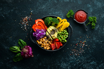 Fototapeta na wymiar Buddha bowl: chickpeas, avocados, broccoli, paprika, green peas, tomatoes. Vegetable salad. Top view. Free space for your text.