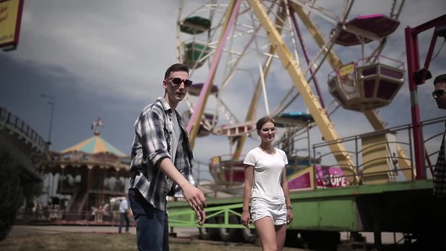 Friends hi five on a Ferris wheel background have fun traveling around the cities of the country together. Two guys and girl met together downtown. Travel concept. Prores 422.