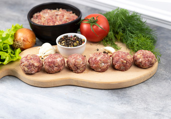 Raw meatballs on the wooden cutting board