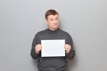 Portrait of confident man holding white blank paper sheet in hands