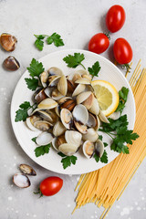 seafood pasta ingredients: clams, spaghetti, tomatoes and parsley. recipe for traditional Italian pasta Spaghetti alle Vongole. on a gray background. top view, food flat lay