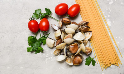 Fototapeta na wymiar seafood pasta ingredients: clams, spaghetti, tomatoes and parsley. recipe for traditional Italian pasta Spaghetti alle Vongole. on a gray background. top view, food flat lay