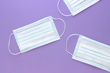 three white medical mask to protect the face from the virus on a blue purple background with space for text