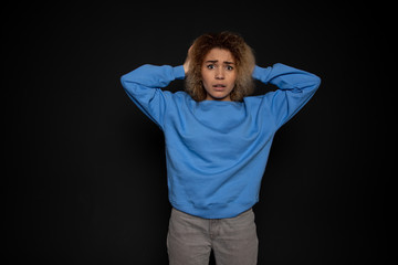 young woman experiencing anxiety and fear, standing on a blank black background
