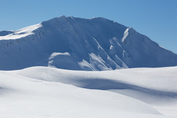 Fototapeta na wymiar snow covered Sandhubel mountain summit near Arosa in winter, blue sky