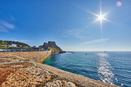 Image of the back of the pier of Gorey Harbour with Gorey Castle in the background with a clam sea, sunshine with a blue sky taken early morning. Jersey,Channel Islands, UK
