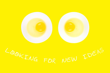 Raw eggs in bowls looking like eyes on smiling face, and text Looking For New Ideas on yellow background. Minimal creative idea concept for startup and business.