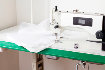 female hands hold a piece of natural cotton fabric near the sewing machine.