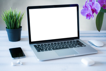 Fototapeta premium Laptop computer white blank screen on work table front view. Copy space, home and office workspace concept, laptop mockup.