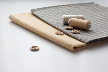 Sewing tools on a white background. A set of fabrics with a pattern, threads, buttons, scissors. sewing workshop atelier for sewing clothes. copy space.