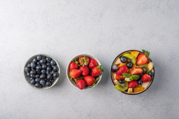 Fresh fruit salad with different ingredients on light wooden background. Healthy diet. Copy space for text. Top view