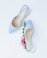 Trendy blue high heel shoes with pink eustoma flowers. Flat lay, top view. Blogging Beauty Concept. Pale blue women's shoes. Copy space.