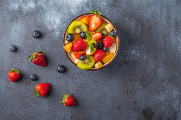 Fresh fruit salad with different ingredients on dark background. Healthy diet. Copy space for text. Top view