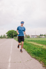 Fototapeta premium A young athlete in a blue T-shirt runs around the stadium