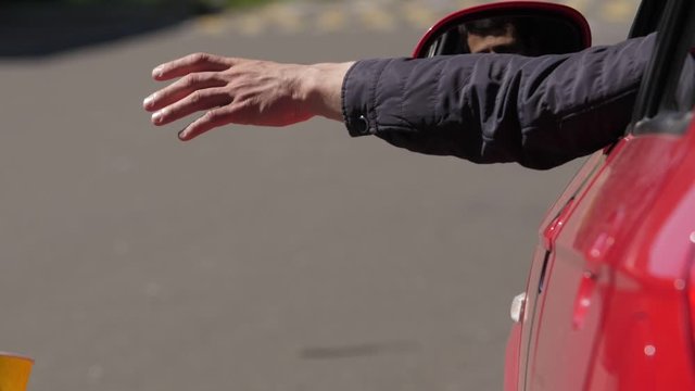 A man throws out a plastic cup from the car