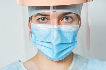 Fototapeta na wymiar Doctor is wearing medical costume, mask and visor. Concept of heroism medical staff during coronavirus outbreak.